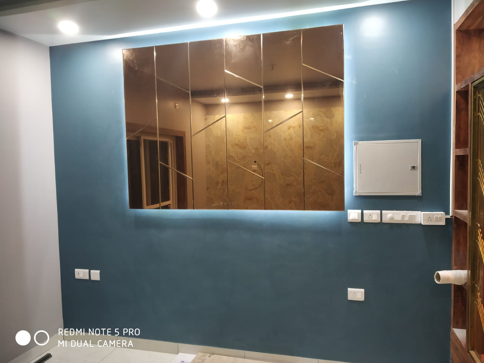 Umer's Residence, Bengaluru — Teal feature wall with a bevelled bronze mirror panel and cove lighting