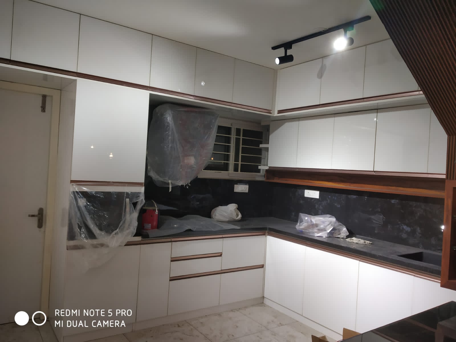 Umer's Residence, Bengaluru — L-shaped modular kitchen in white glossy laminate with rose-gold profile handles