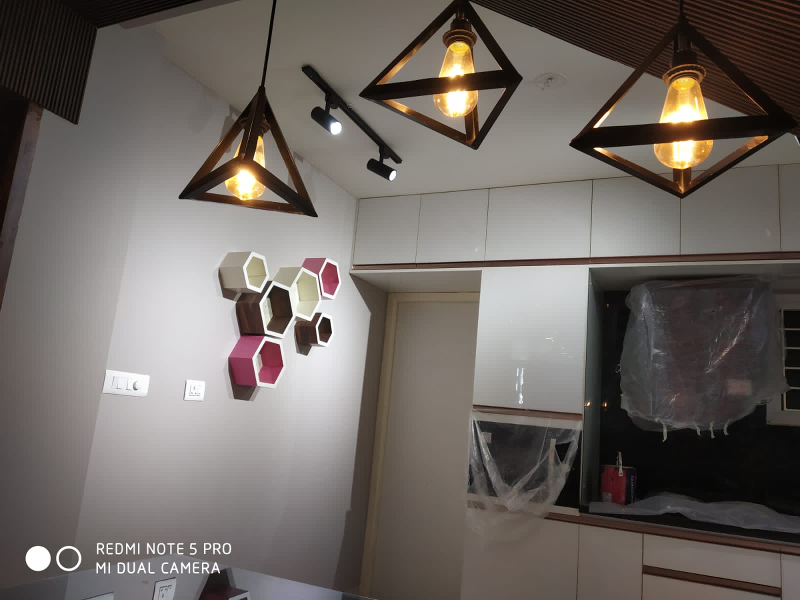 Umer's Residence, Bengaluru — Geometric pendant cluster over the dining counter with hexagon wall decor