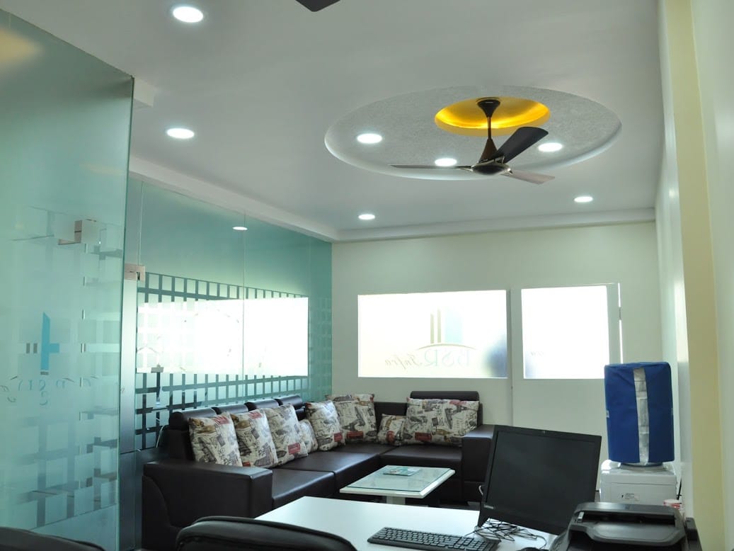 BSR Infra Office, Ballari — Entry sitout lounge with leather seating and frosted glass branding panels