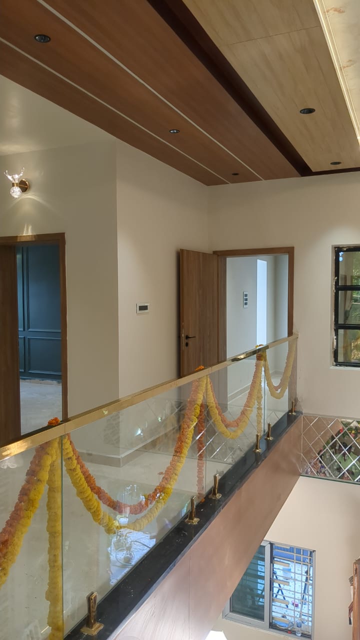 Ajay's House, Ballari — Double-height landing with glass railing and wooden false ceiling