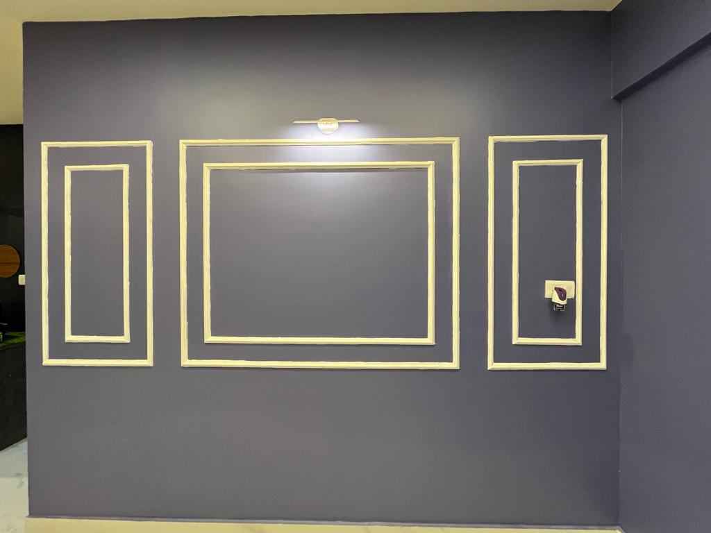 Rohan's Flat, Bangalore — Charcoal feature wall with gold moulding frames and a picture light