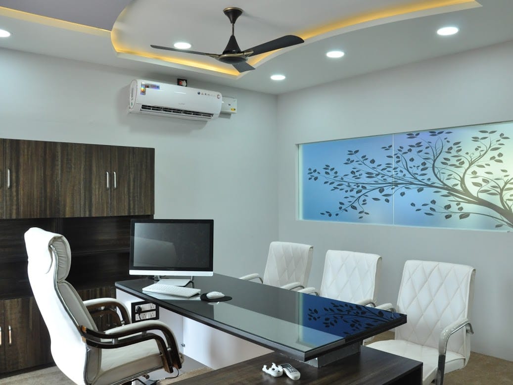 BSR Infra Office, Ballari — Director's cabin with glass-top desk, storage unit and illuminated tree mural