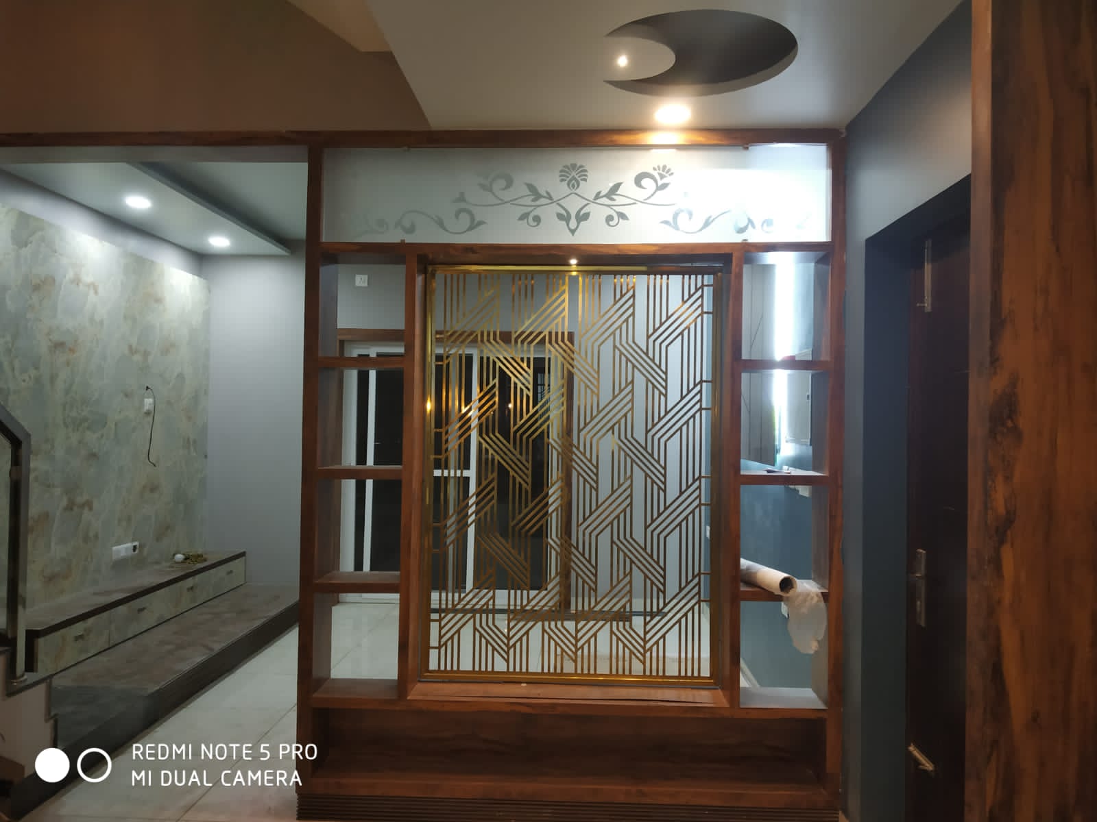 Umer's Residence, Bengaluru — Foyer partition in gold laser-cut metal with etched glass and stencilled motif band